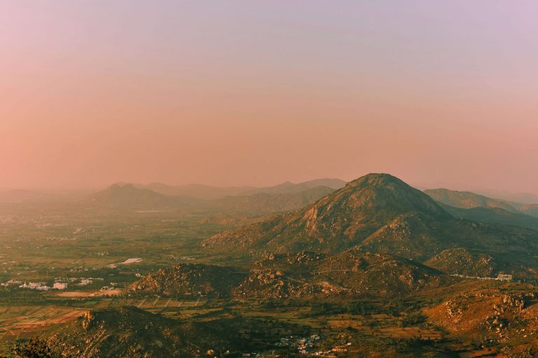 pink tinted sky with towns that look small compared to the surrounding hills